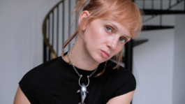 Portrait der Künstlerin Ida Kammerloch für die Biennale für Freiburg 3, 2025. Si eist vor wird einer Wendeltreppe und hellem Hintergrund.